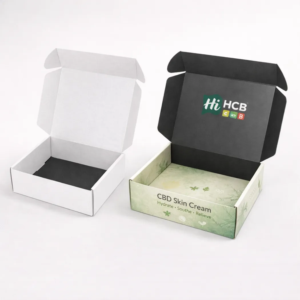 Two open cardboard mailing boxes showing a black interior lid and a branded botanical product base- class=